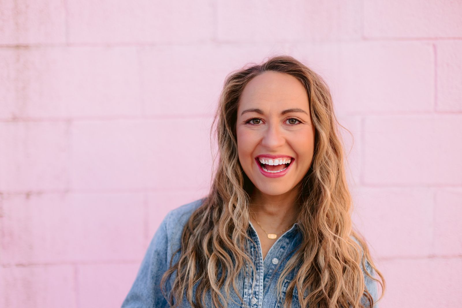 Kate Downing smiling in front of a pink wall